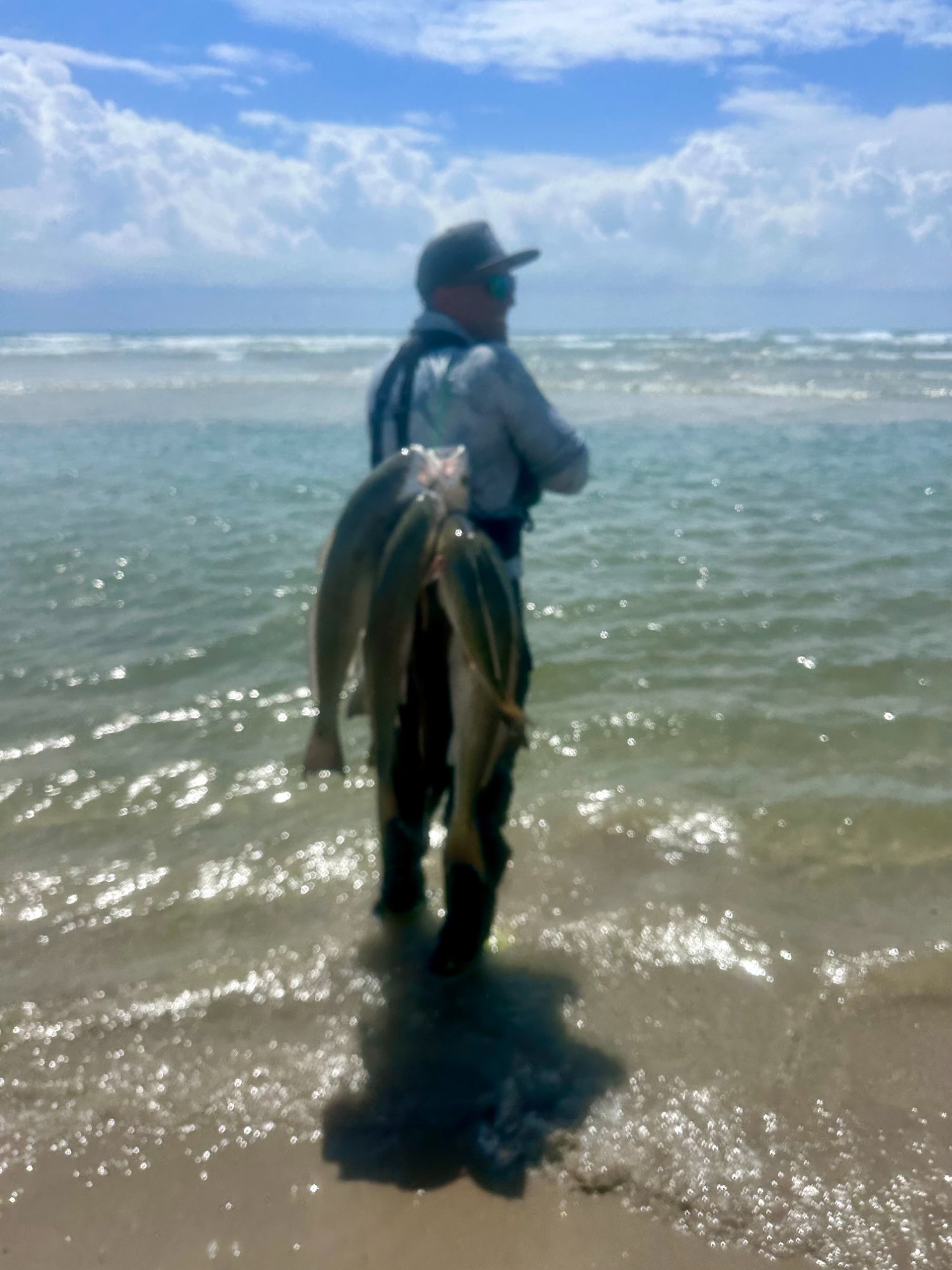 Angler on the Cedar Bayou surf beach at moonrise with a stringer of fish